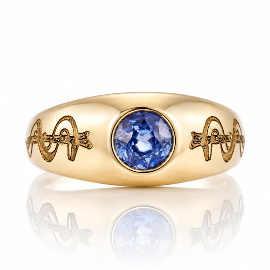 A gold ring with a blue gemstone in the center, featuring intricate engraved designs on the band.