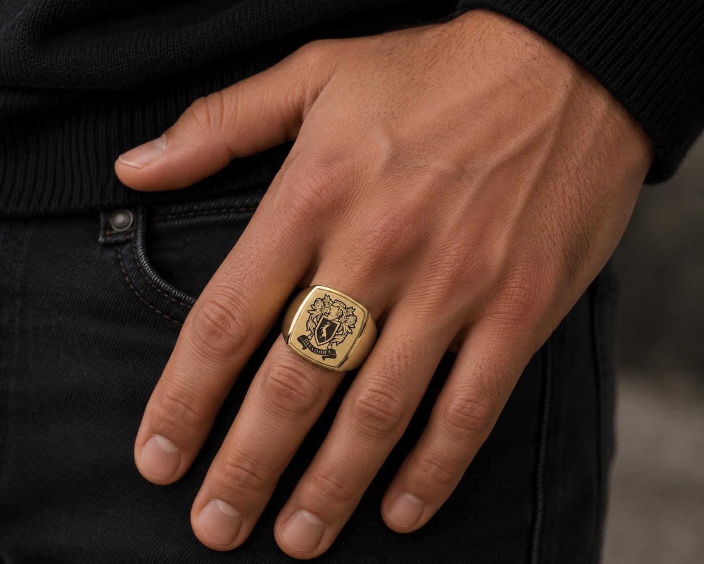 A close-up of a person's hand wearing a gold ring with a crest design.