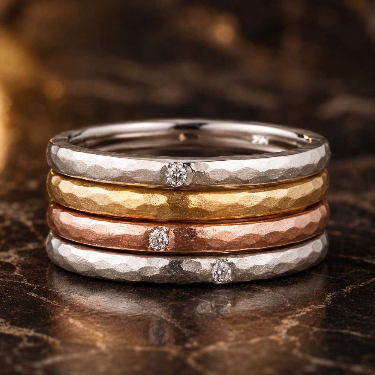 A stack of three rings with a diamond set in each, arranged on a marble surface.