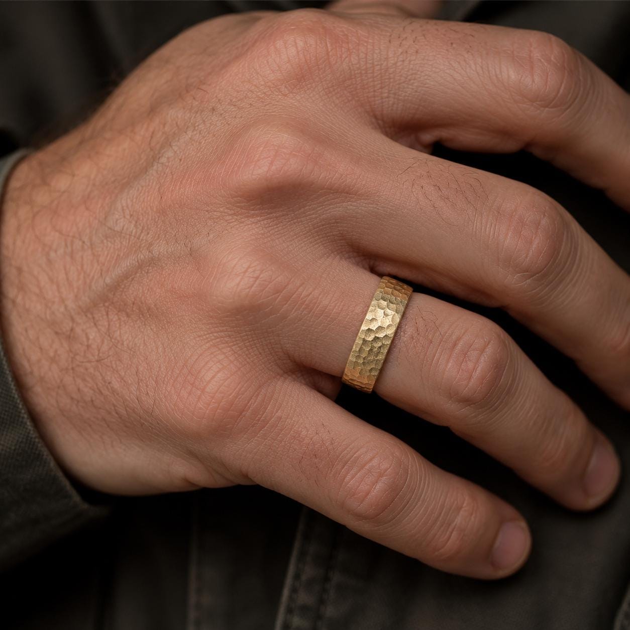 A close-up of a person's hand wearing a gold ring on the ring finger.