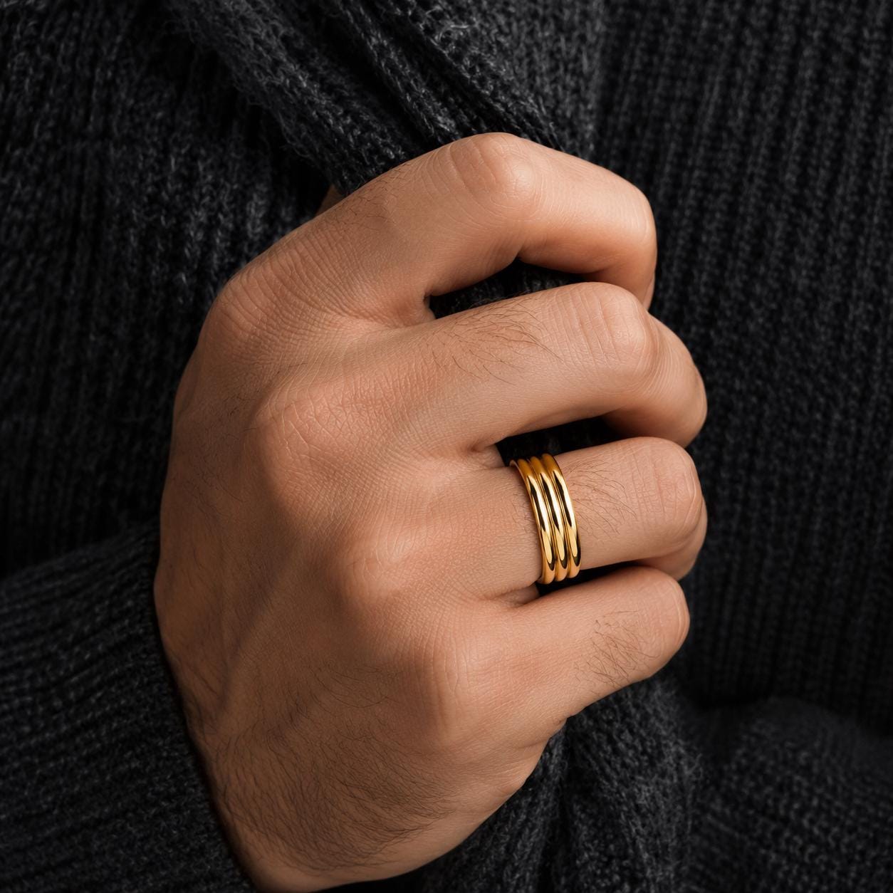 A close-up of a person's hand wearing a gold ring on the ring finger.