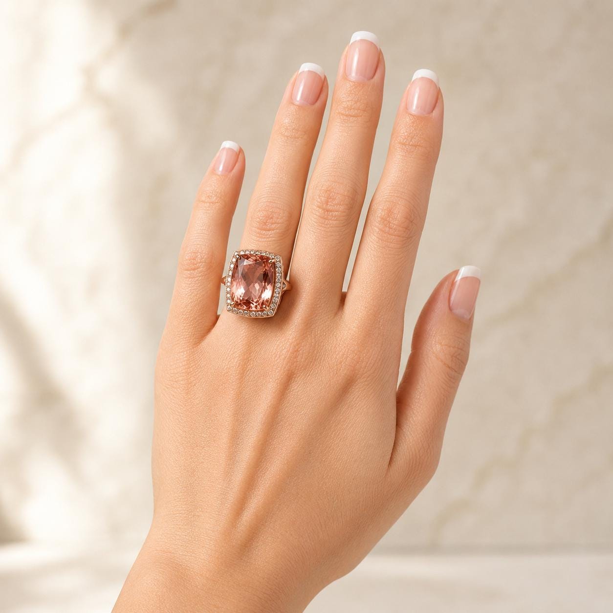 A close-up of a hand wearing a large, pink gemstone ring on the ring finger.