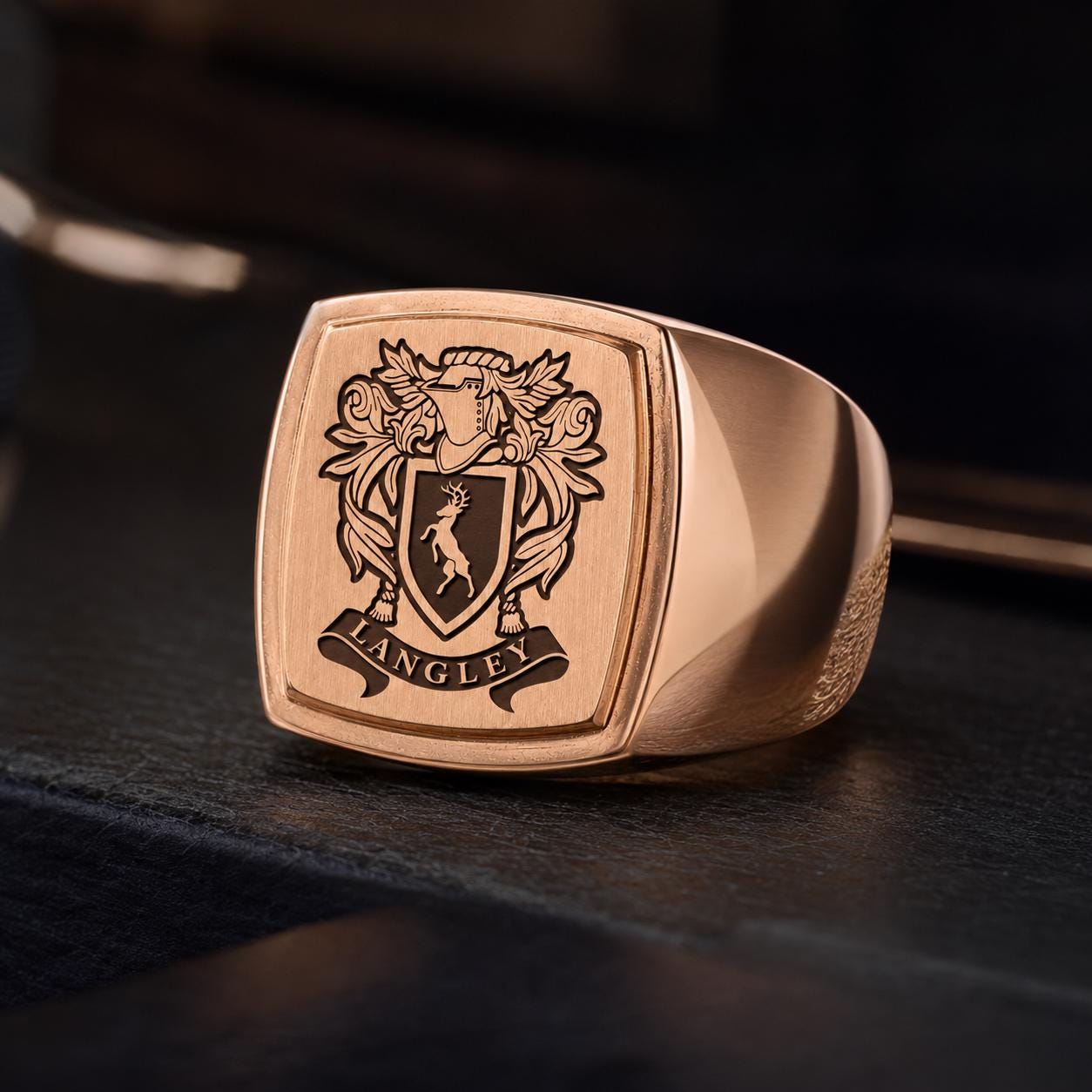 A gold-colored ring with a crest design on it, featuring a shield with a lion and the word "ANGLEY" written on it.