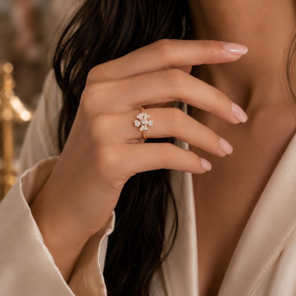 A close-up of a person's hand wearing a gold ring with a diamond cluster, with their hair visible.