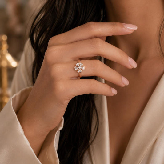 A close-up of a person's hand wearing a gold ring with a diamond cluster, with their hair visible.