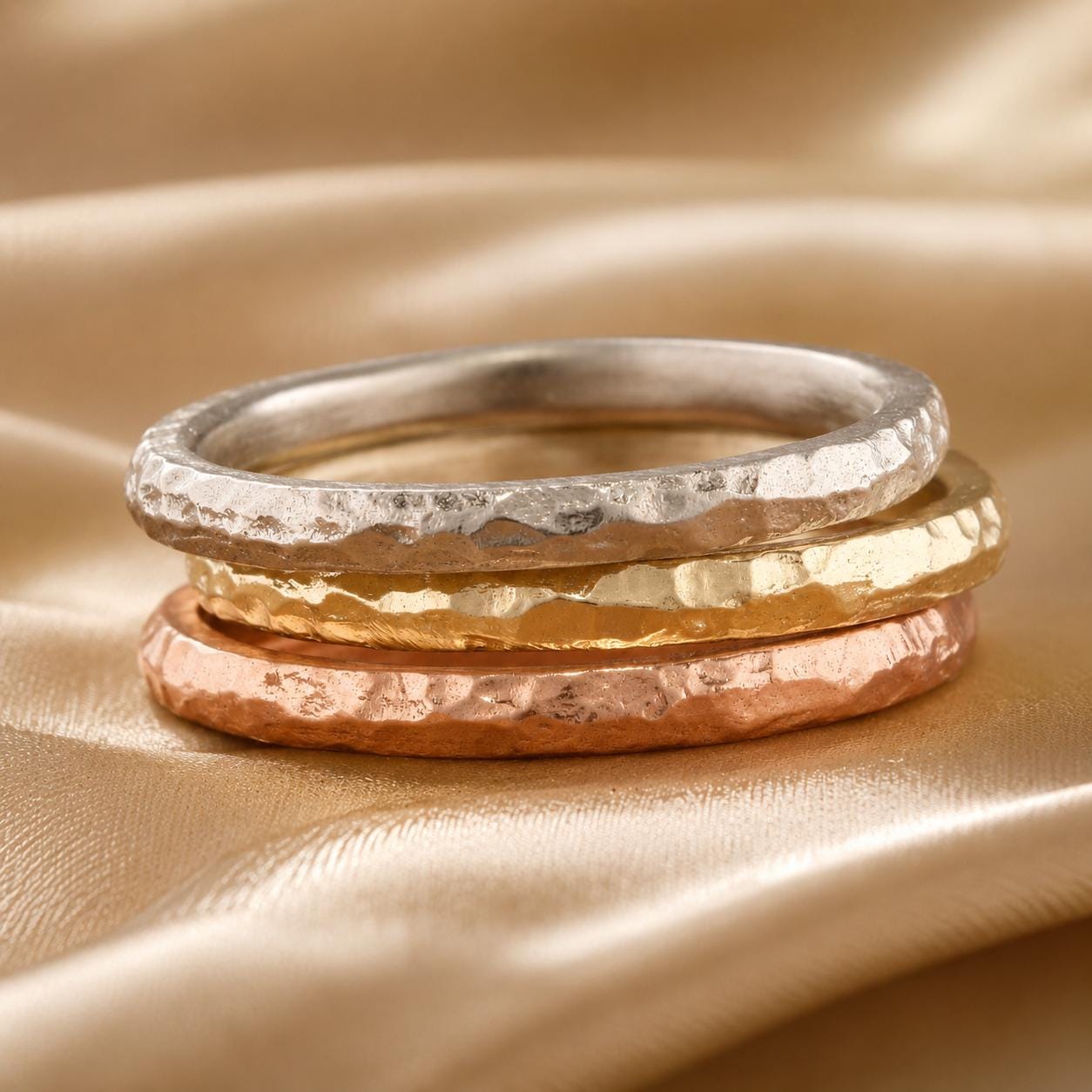 A stack of three rings on a golden fabric background.