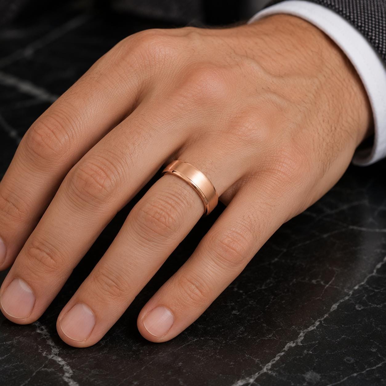 A close-up image of a person's hand wearing a gold wedding ring on the ring finger.