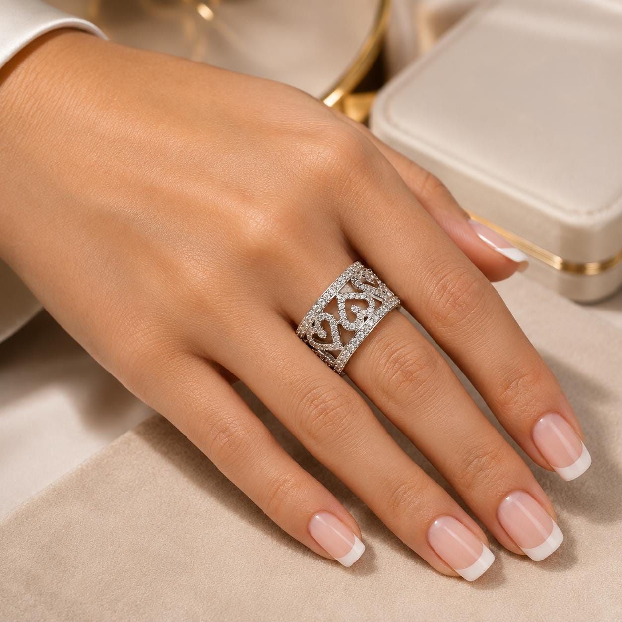 A close-up of a hand wearing a ring with a decorative band, resting on a beige surface.