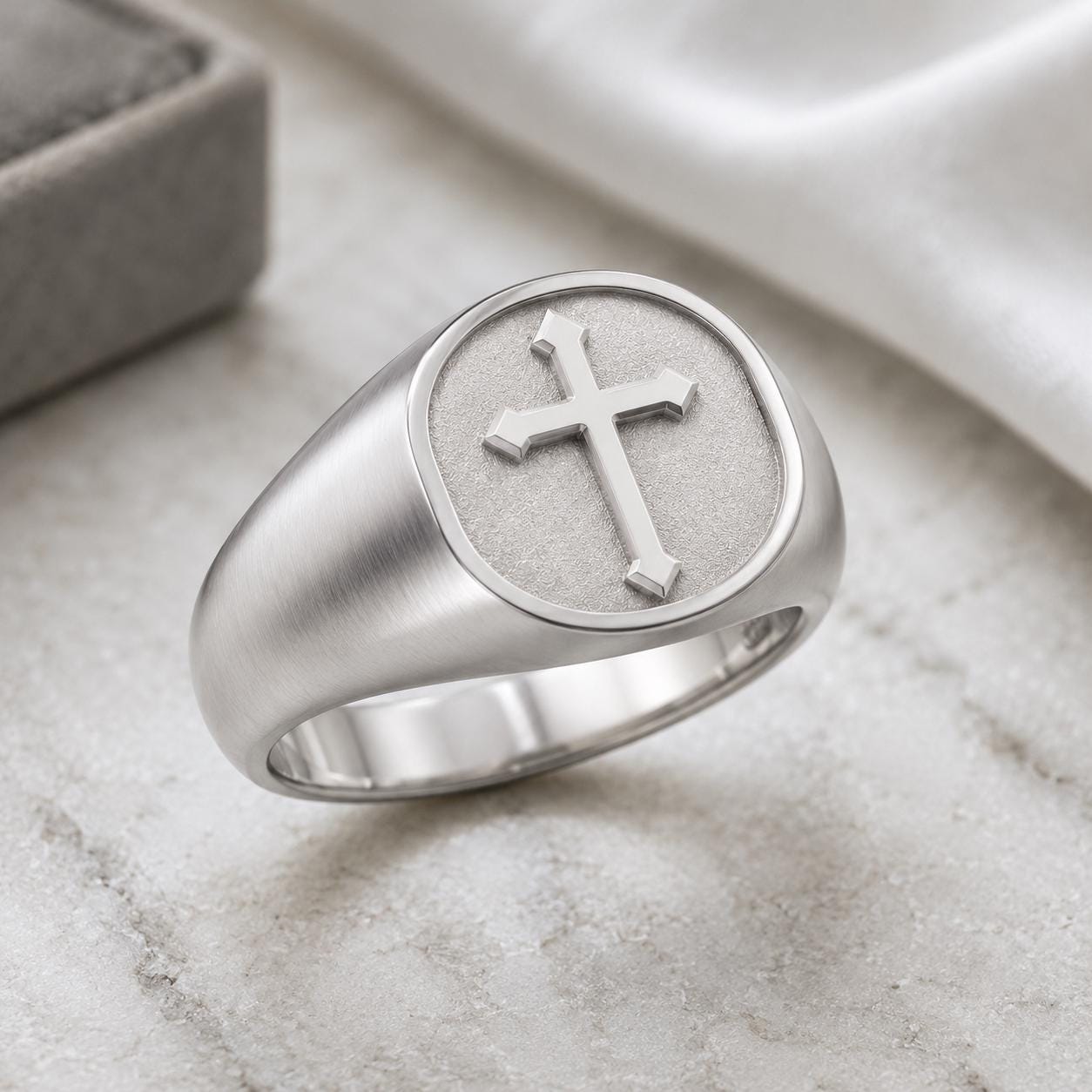 A silver ring with a cross design on the surface.