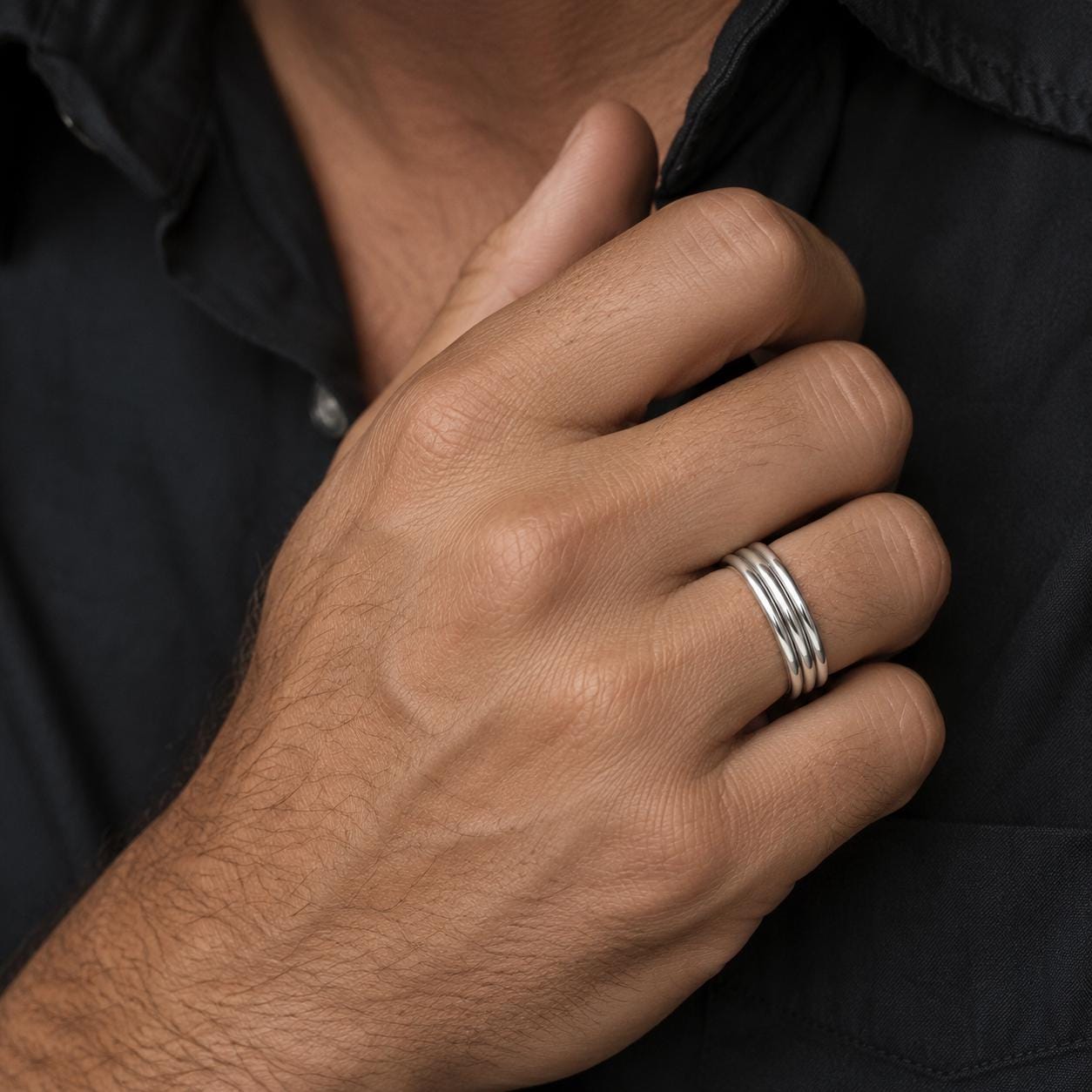 A close-up of a person's hand wearing a silver ring on the ring finger.