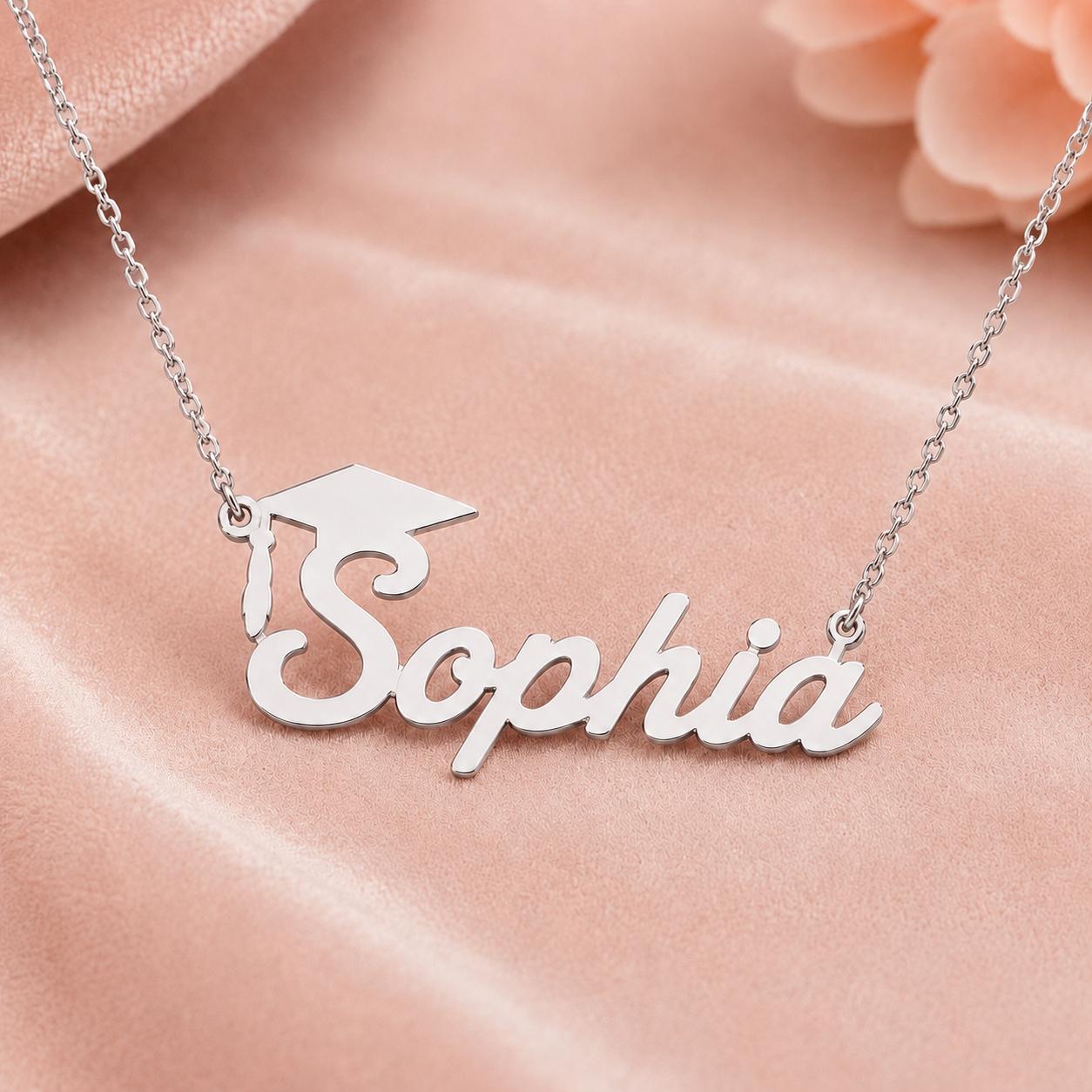 A necklace with the name "Sophia" engraved on it, displayed on a pink fabric background.