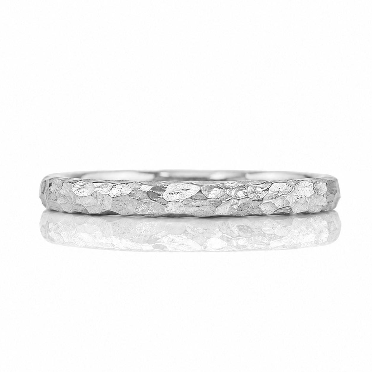 A silver ring with a textured surface, reflecting light and creating a shiny appearance.
