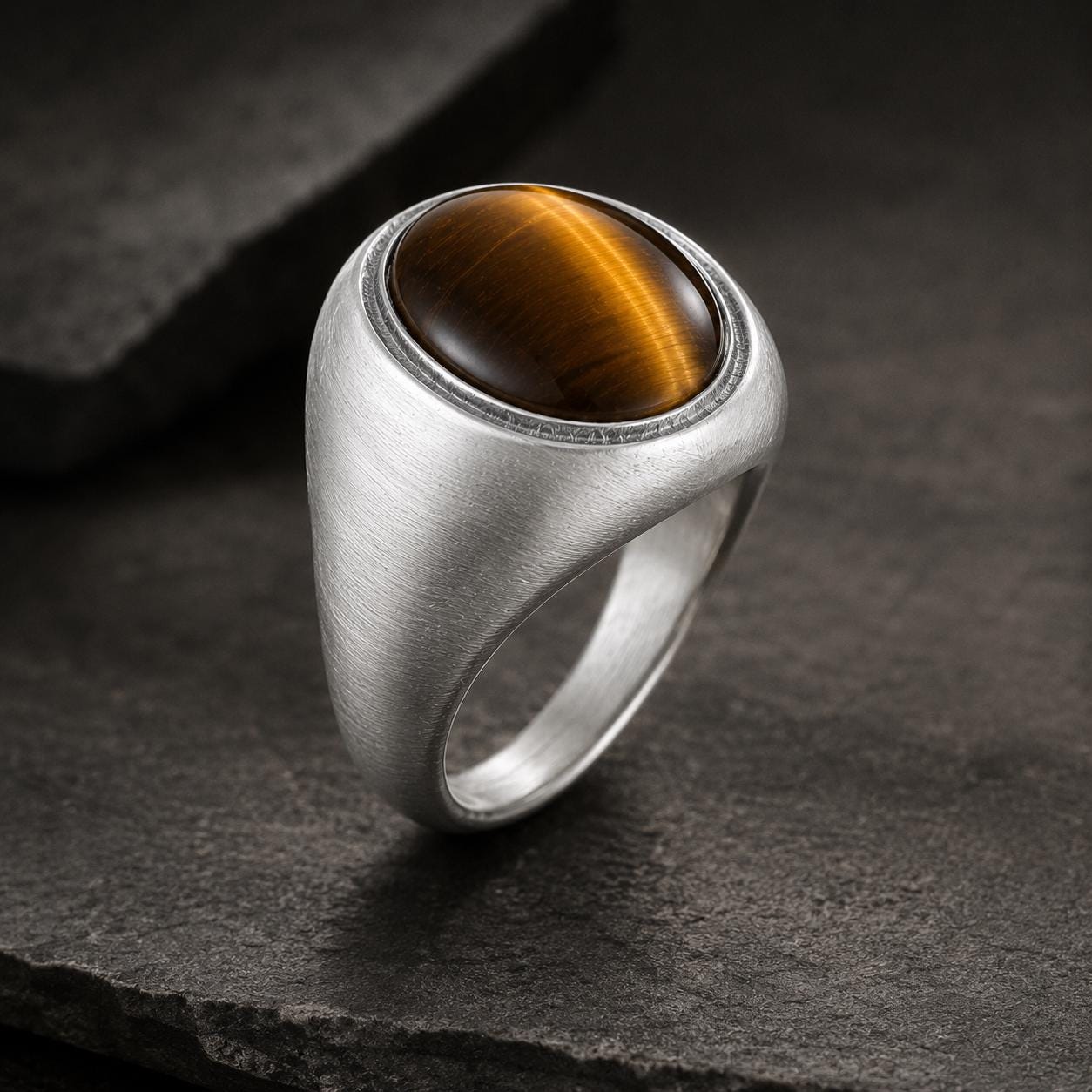 A silver ring with a large, round, amber-colored gemstone, possibly a tiger eye, set in the center of the ring.