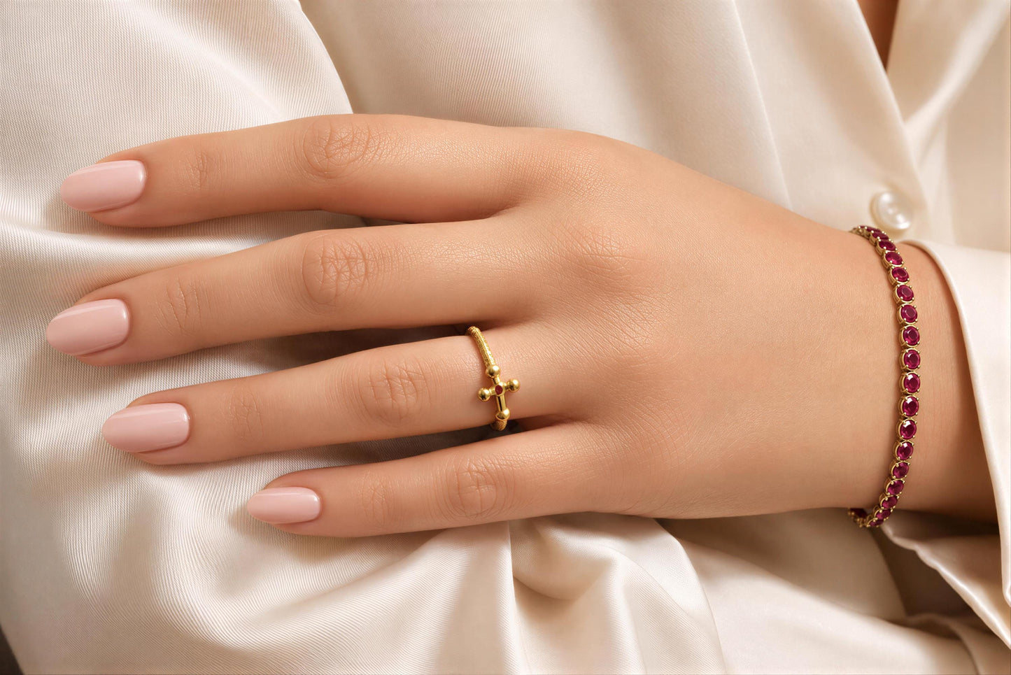A close-up of a hand wearing a gold ring and bracelet on a white background.