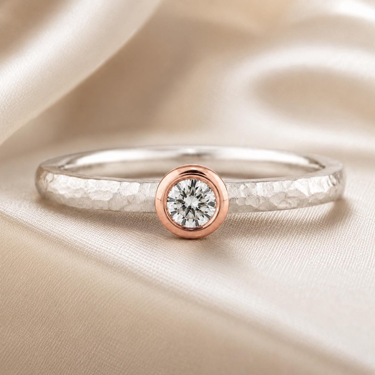 A close-up image of a silver ring with a large, round diamond set in the center, resting on a beige fabric background.