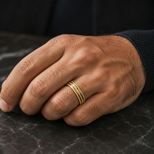 A close-up image of a hand wearing a gold ring on the ring finger.
