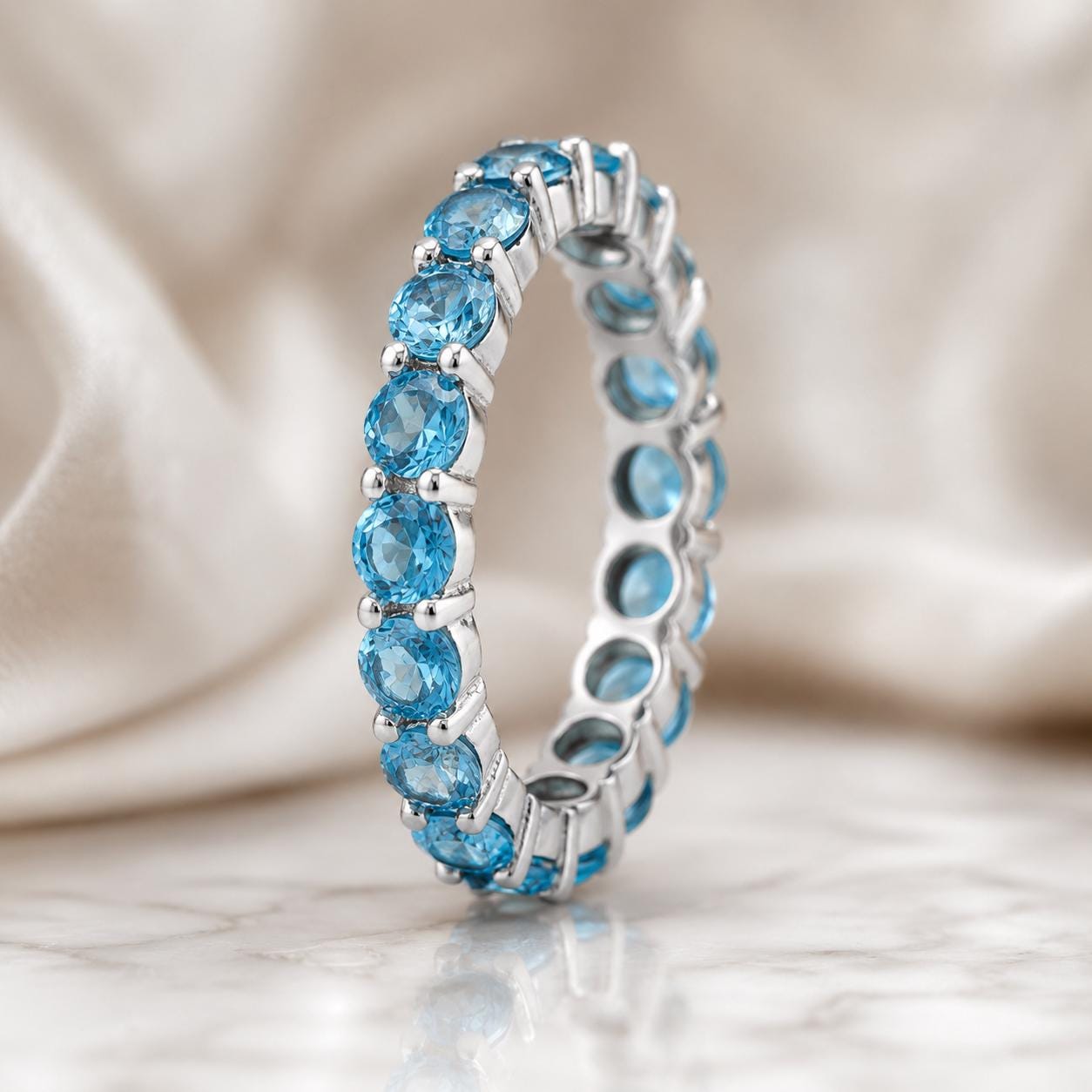 A silver ring with a row of blue gemstones, likely aquamarine, set in a delicate band.