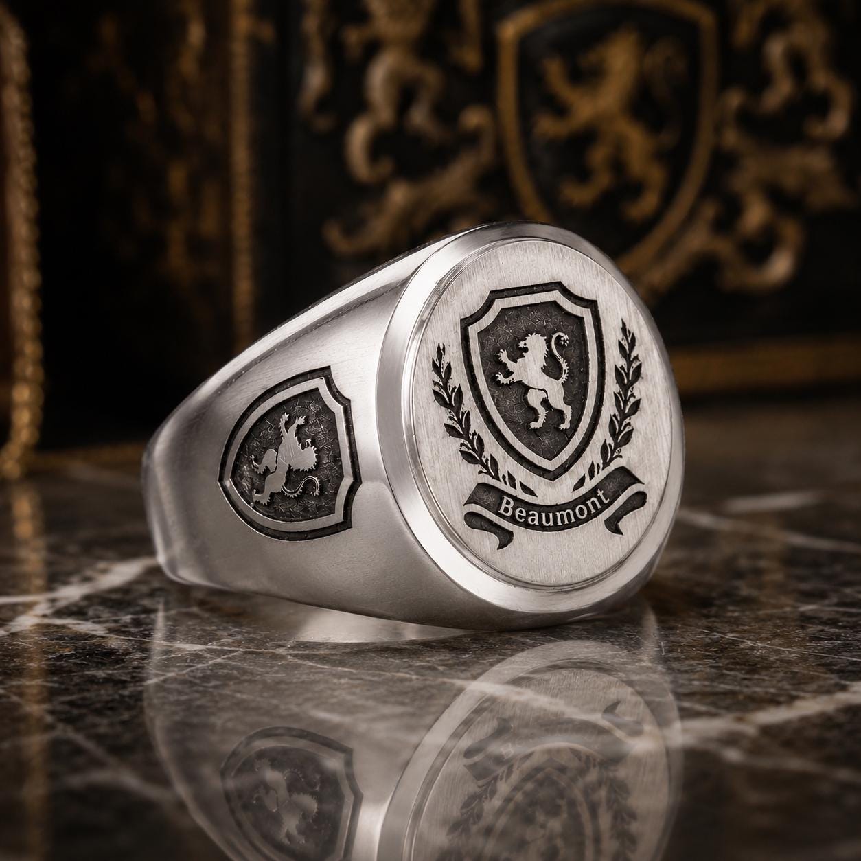 A silver ring with a shield-shaped emblem featuring a lion and laurel wreath, with the word "Beaumont" inscribed below.