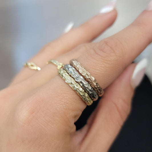 A close-up of a person's hand wearing three rings on the ring finger.