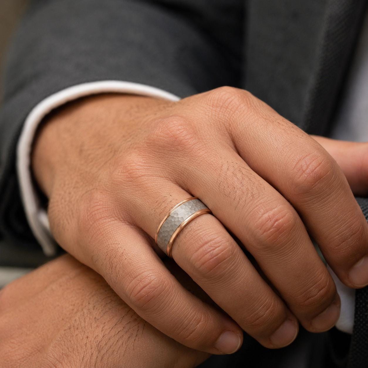 A close-up image of a person's hand wearing a silver ring on the ring finger.