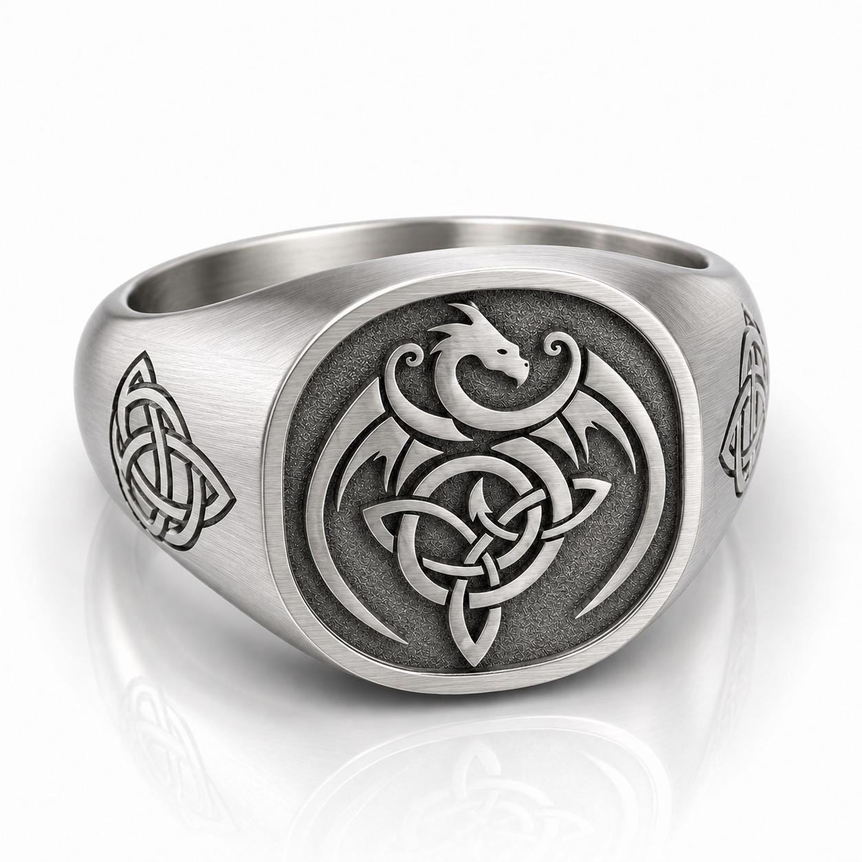 A silver ring with an intricate design featuring a dragon and a Celtic knot pattern.