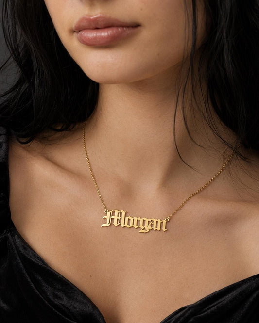 A close-up of a woman wearing a gold necklace with the name "Morgan" engraved on it.