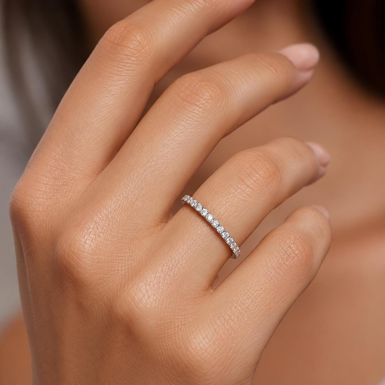 A close-up of a person's hand wearing a diamond-encrusted ring.