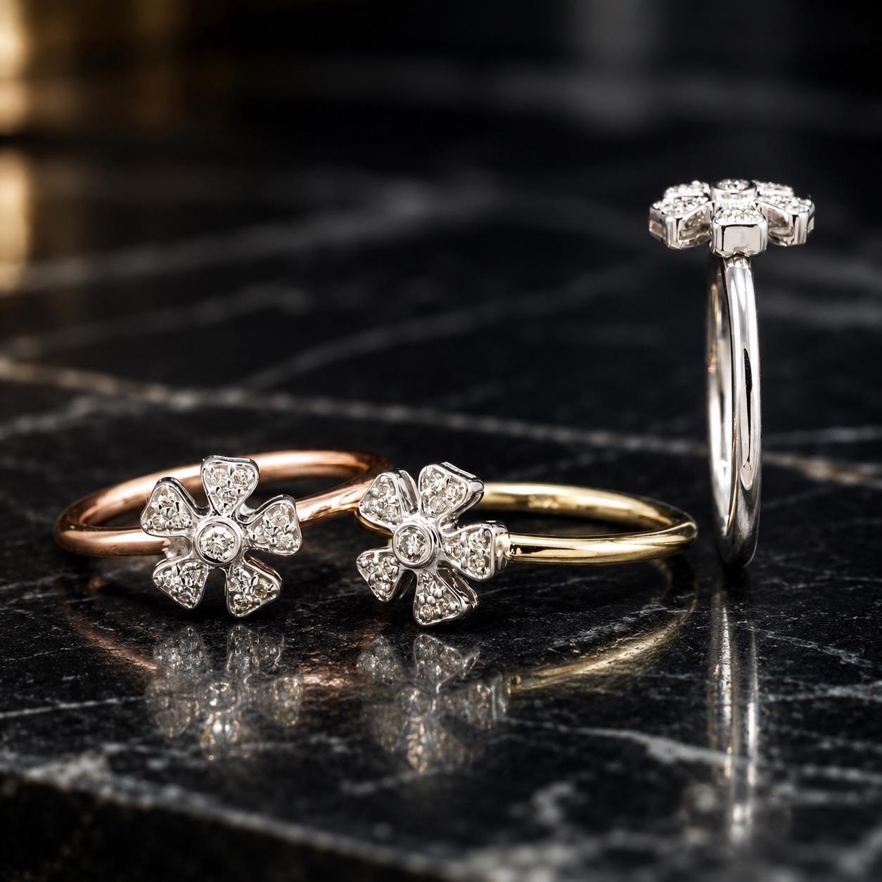 Three diamond-encrusted rings are displayed on a black marble surface, with two rings featuring larger diamonds and one ring with a smaller diamond cluster.