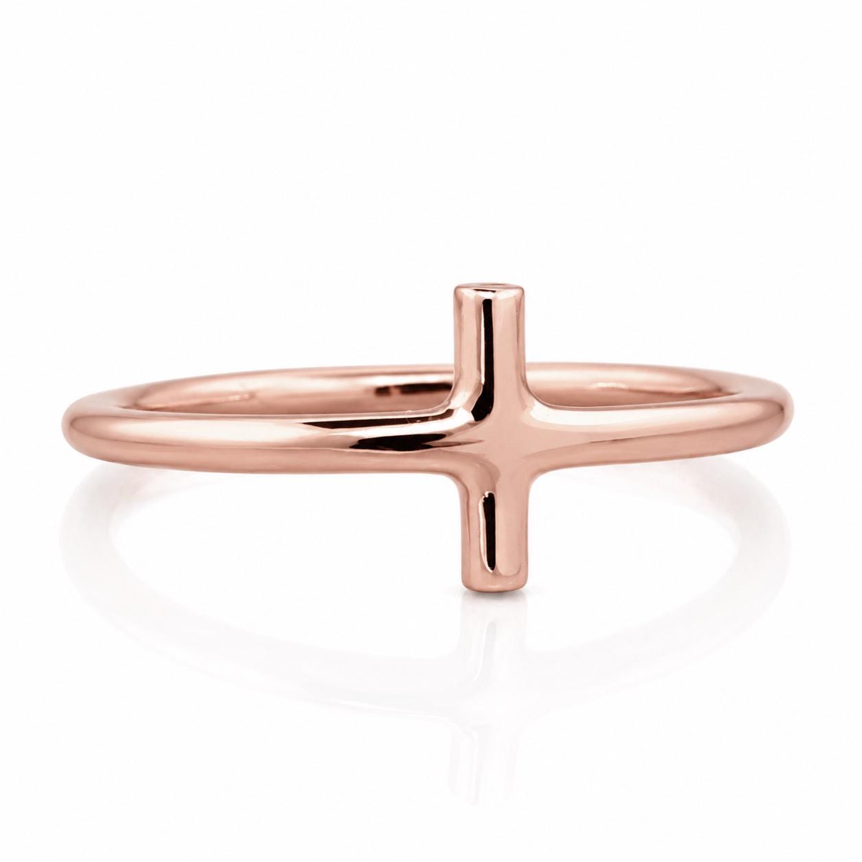 A rose gold ring with a single, thin, elongated cross-shaped element.