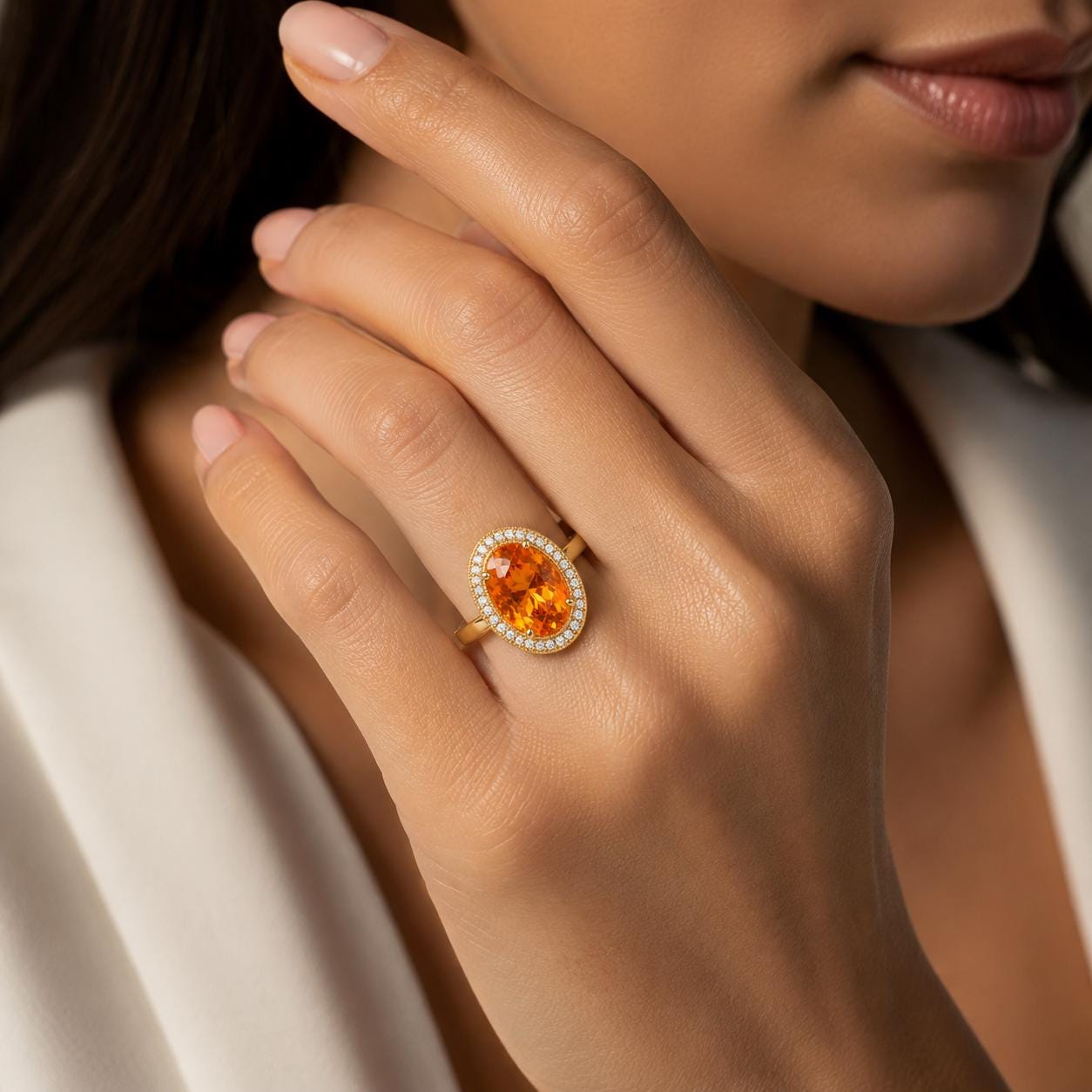 A close-up of a person's hand wearing a gold ring with a large oval-shaped gemstone.