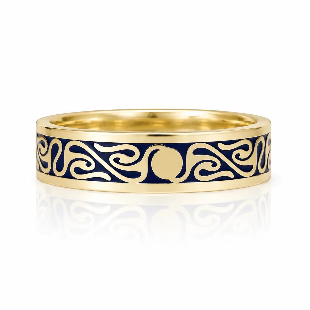 A gold ring with a blue and gold design featuring a central motif and swirling patterns.