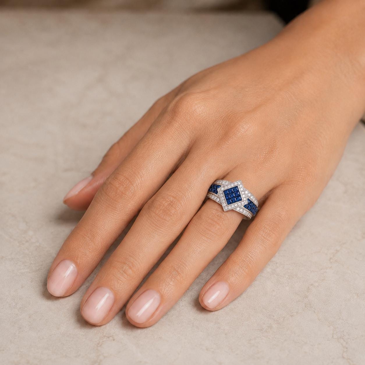 A close-up of a hand wearing a diamond ring with blue gemstones.