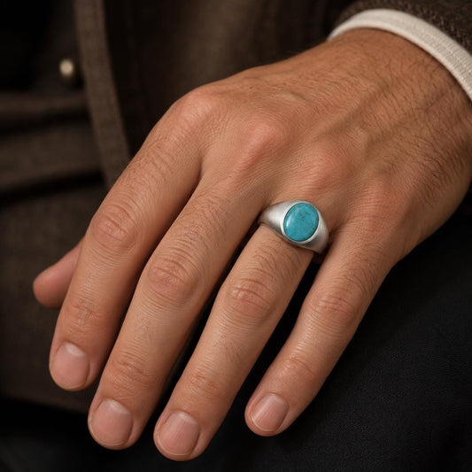 A close-up of a person's hand wearing a silver ring with a turquoise stone.