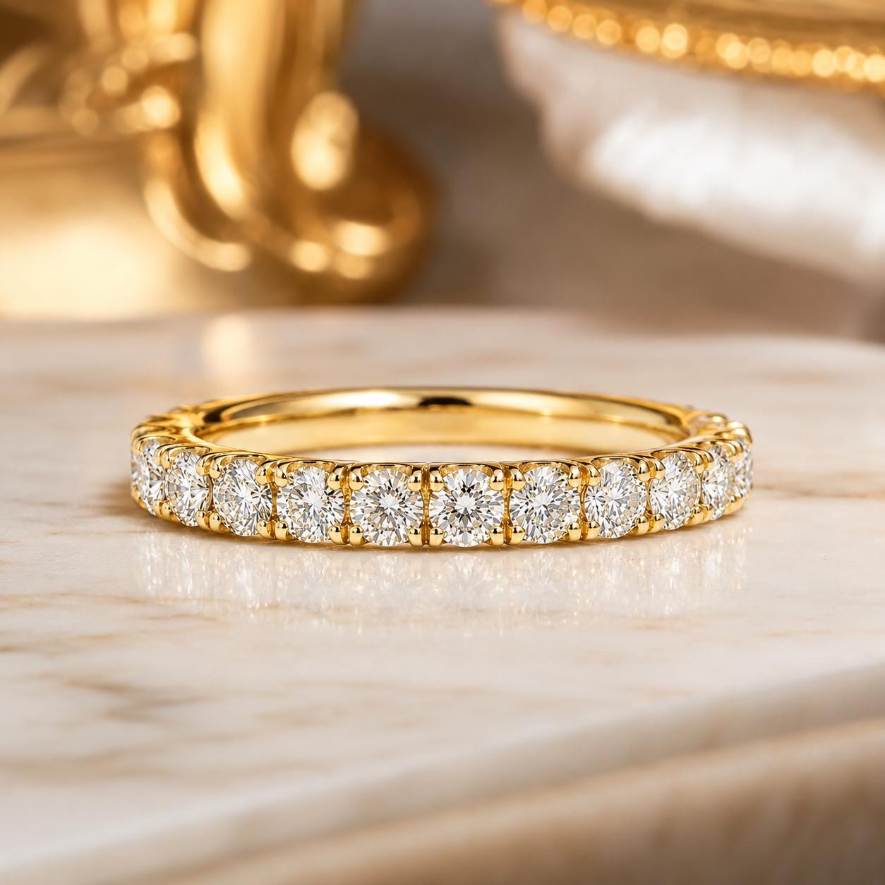 A gold band with a row of diamonds set in it, resting on a marble surface.