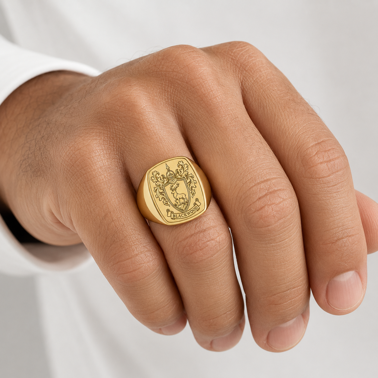A close-up of a person's hand wearing a gold ring with a decorative design.