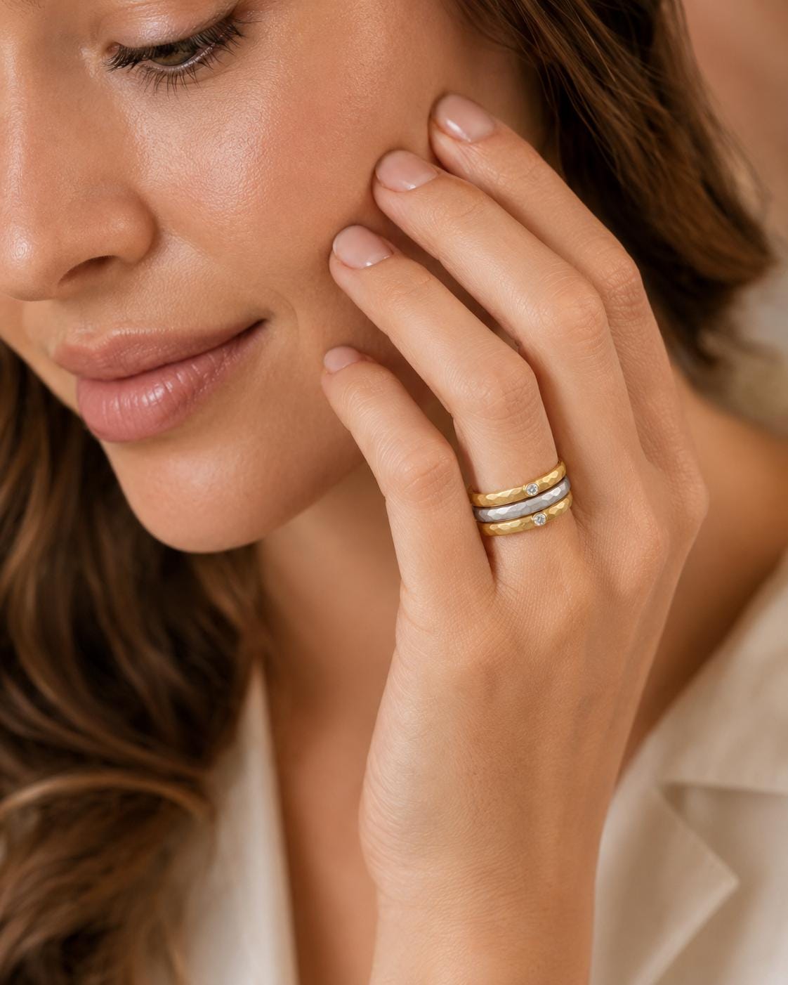 A close-up of a woman's face, focusing on her hand adorned with a ring.