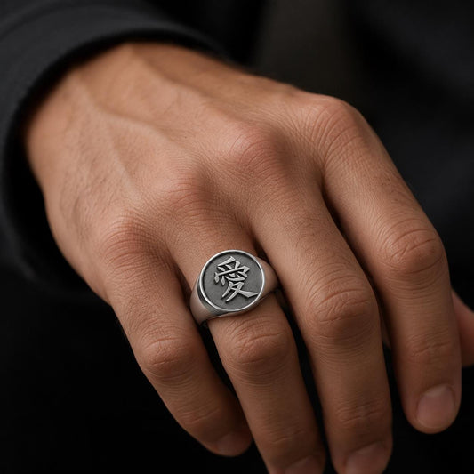 A close-up of a person's hand wearing a silver ring with an engraved symbol on it.