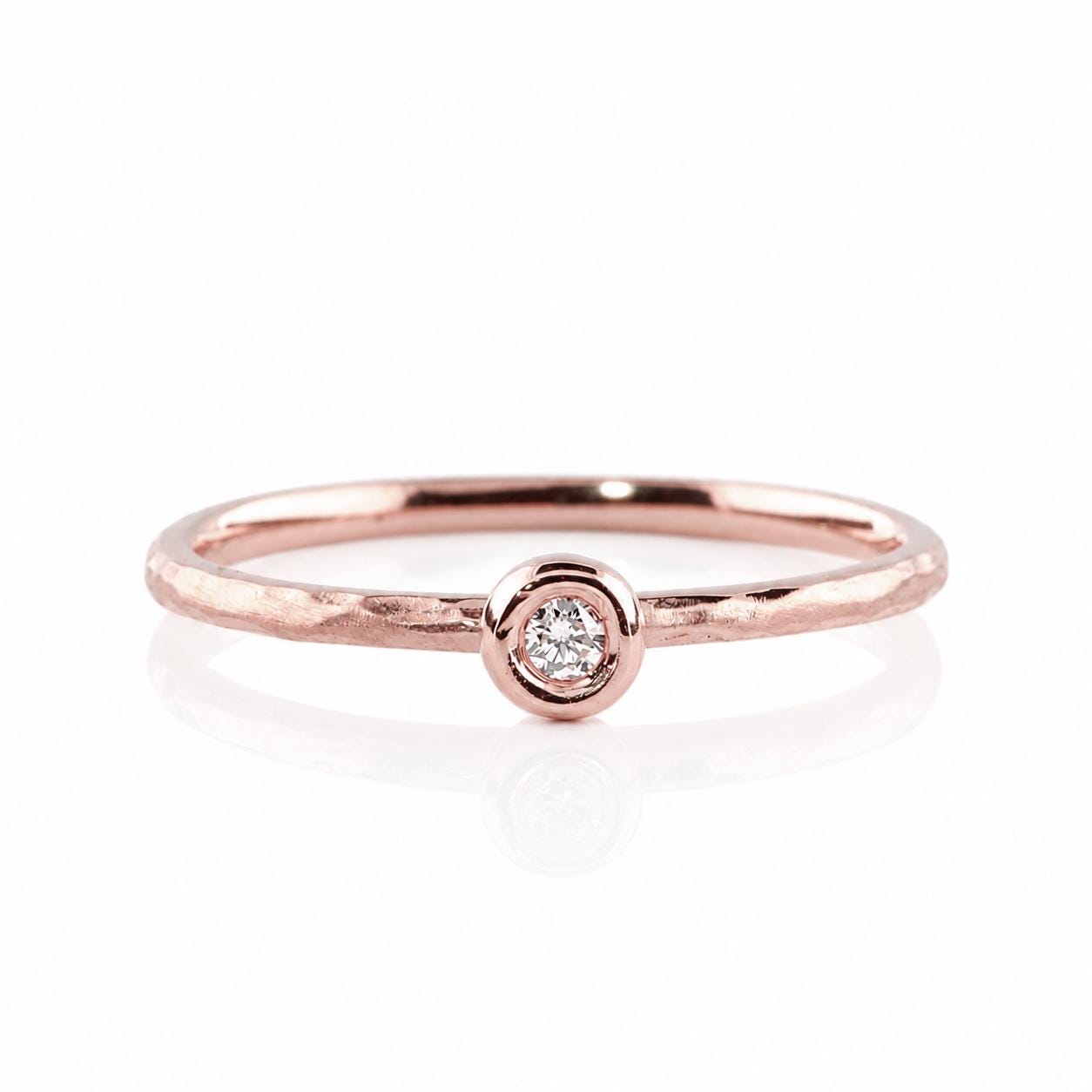 A rose gold ring with a single round diamond set in the center.