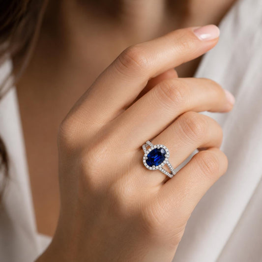 A close-up of a hand wearing a diamond ring with a large blue gemstone.