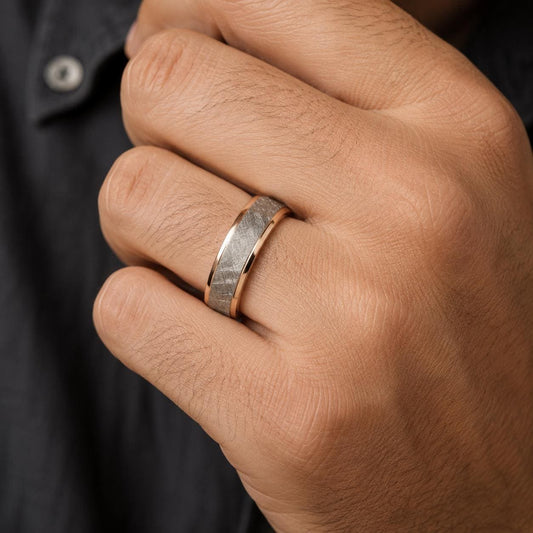 A close-up of a person's hand wearing a gold ring with a gray stone.