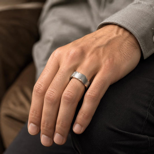 A close-up of a person's hand wearing a silver ring, resting on a person's lap.