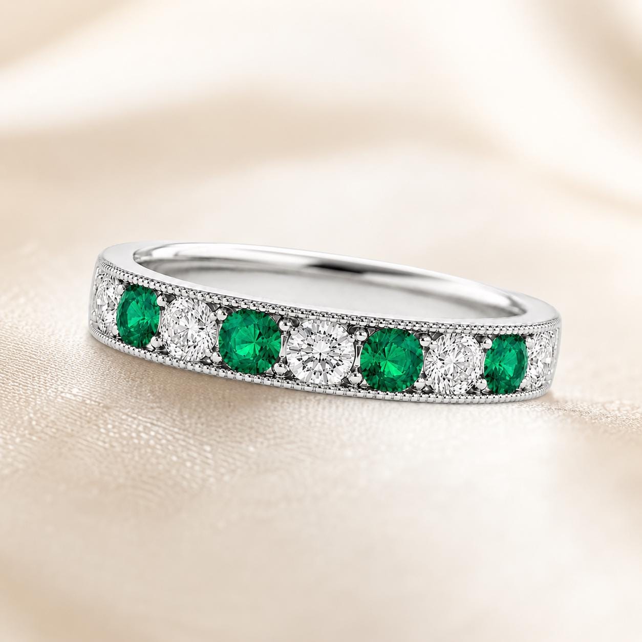 A silver ring with a row of green and white diamonds set in the band.