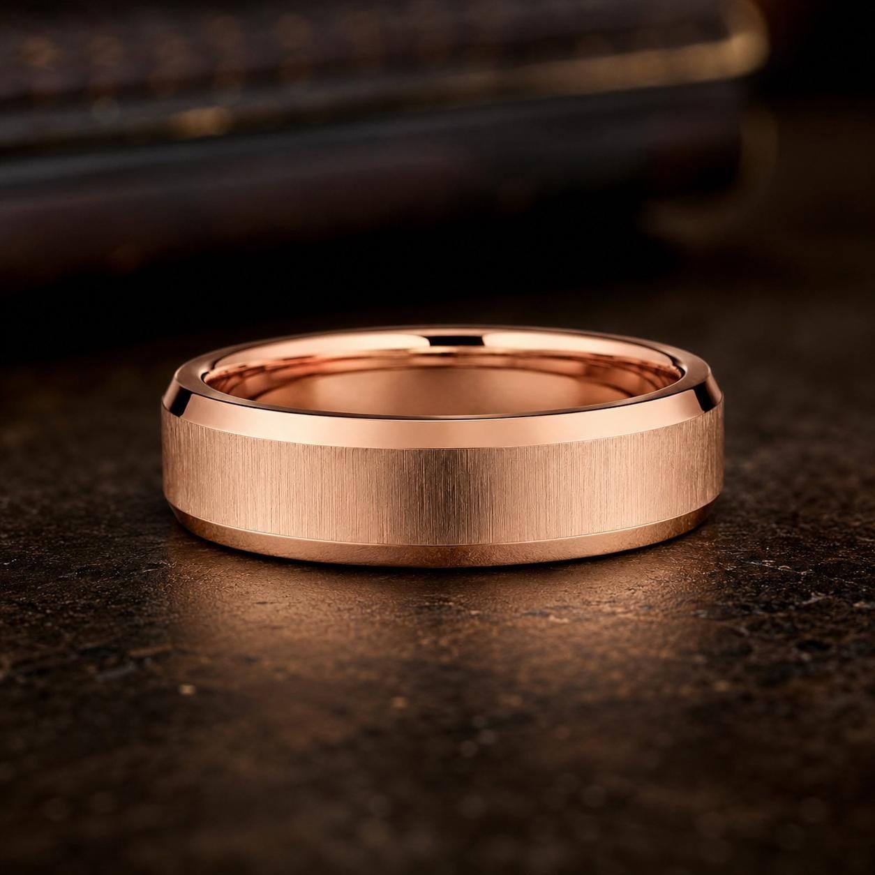 A close-up image of a gold-colored ring with a textured surface, placed on a dark surface.