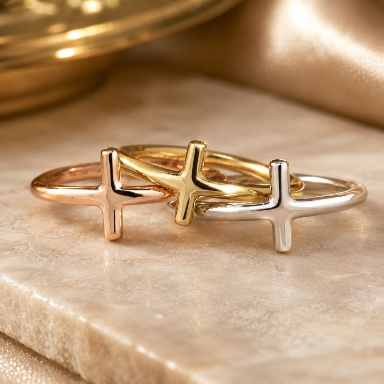 Three rings with a cross design are displayed on a marble surface.