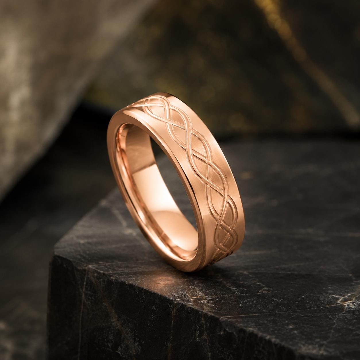 A gold-colored ring with a Celtic knot design is displayed on a black surface.