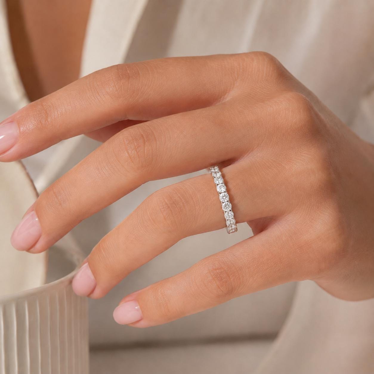 A close-up of a person's hand wearing a diamond ring on the ring finger.