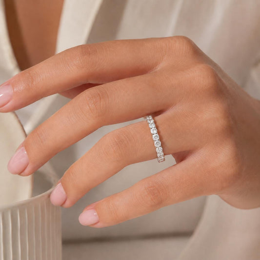A close-up of a person's hand wearing a diamond ring on the ring finger.