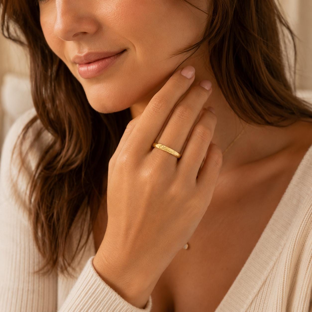 A close-up of a woman's hand wearing a gold ring, with her chin resting on her hand.
