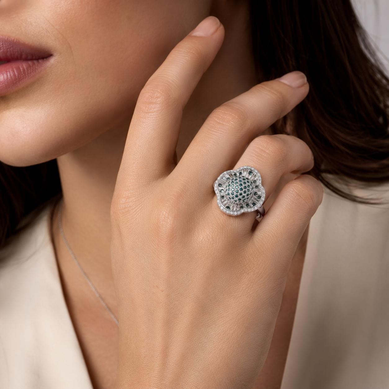 A close-up of a woman's hand wearing a large, ornate ring with a floral design.