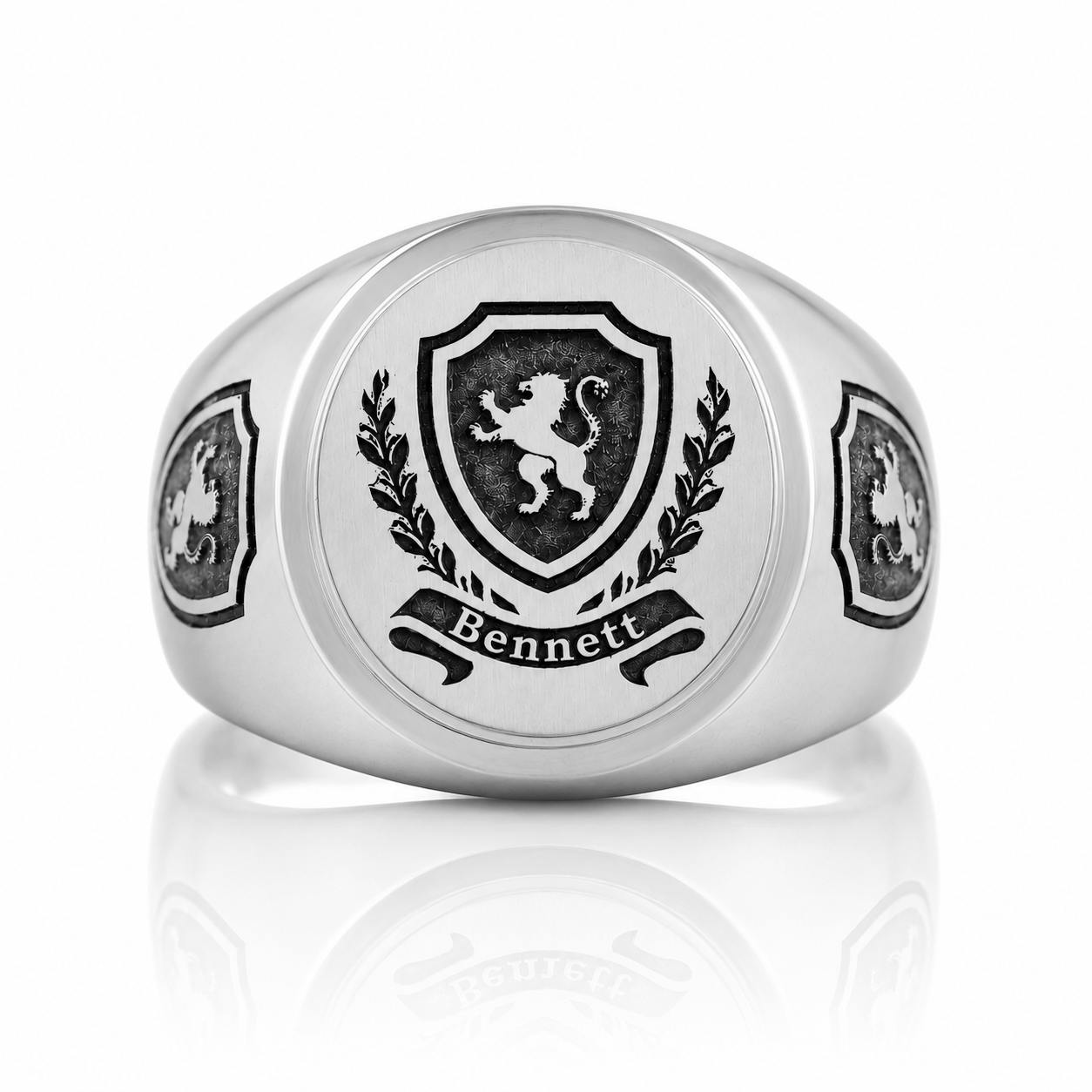 A silver ring with a black and white emblem featuring a lion and laurel wreath, along with the name "Bennett" below the emblem.